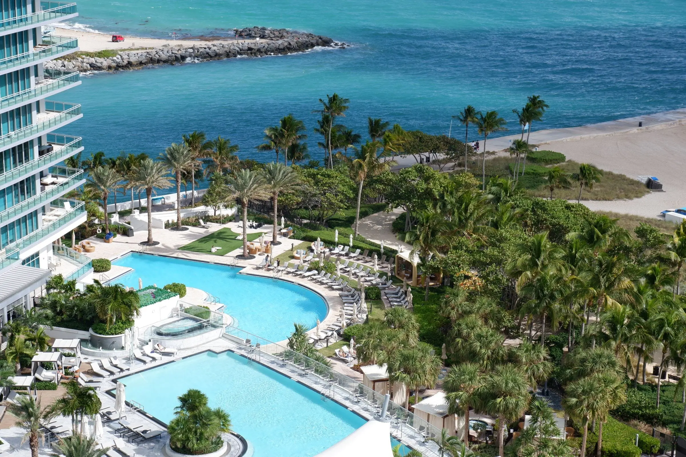 Aerial view of pools and palm trees beside the ocean