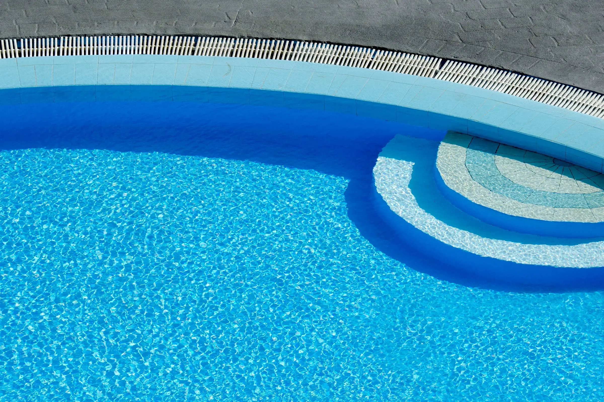 Sunlit blue pool with curved tiled steps